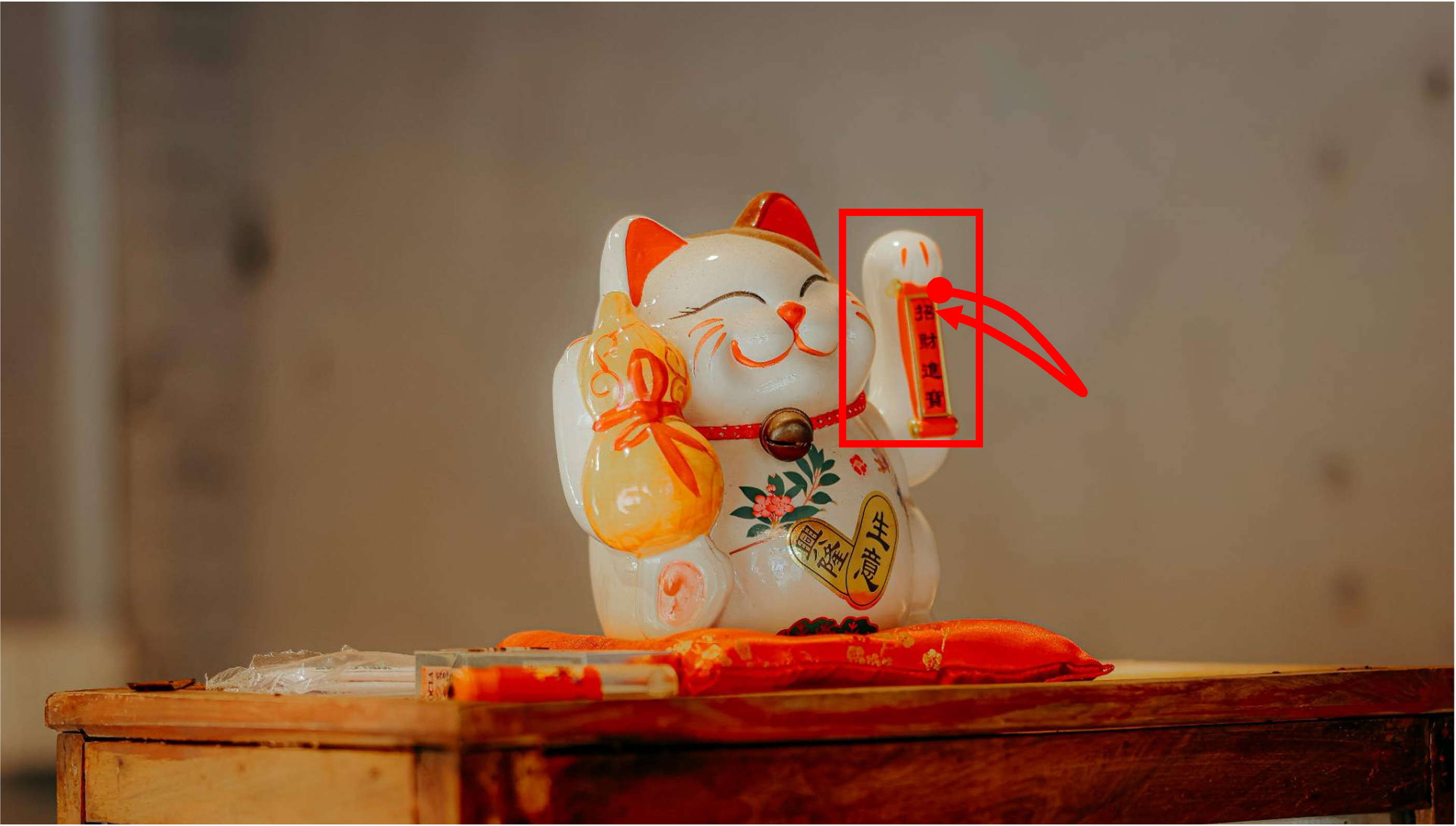 A toy cat is sitting on a table. The toy moves its arm as if it is calling someone. The shot is taken with a static camera. Camera remains stationary. Static Camera. Camera locked down at the same place. The video loops back to the beginning of the video after it reaches the end.
