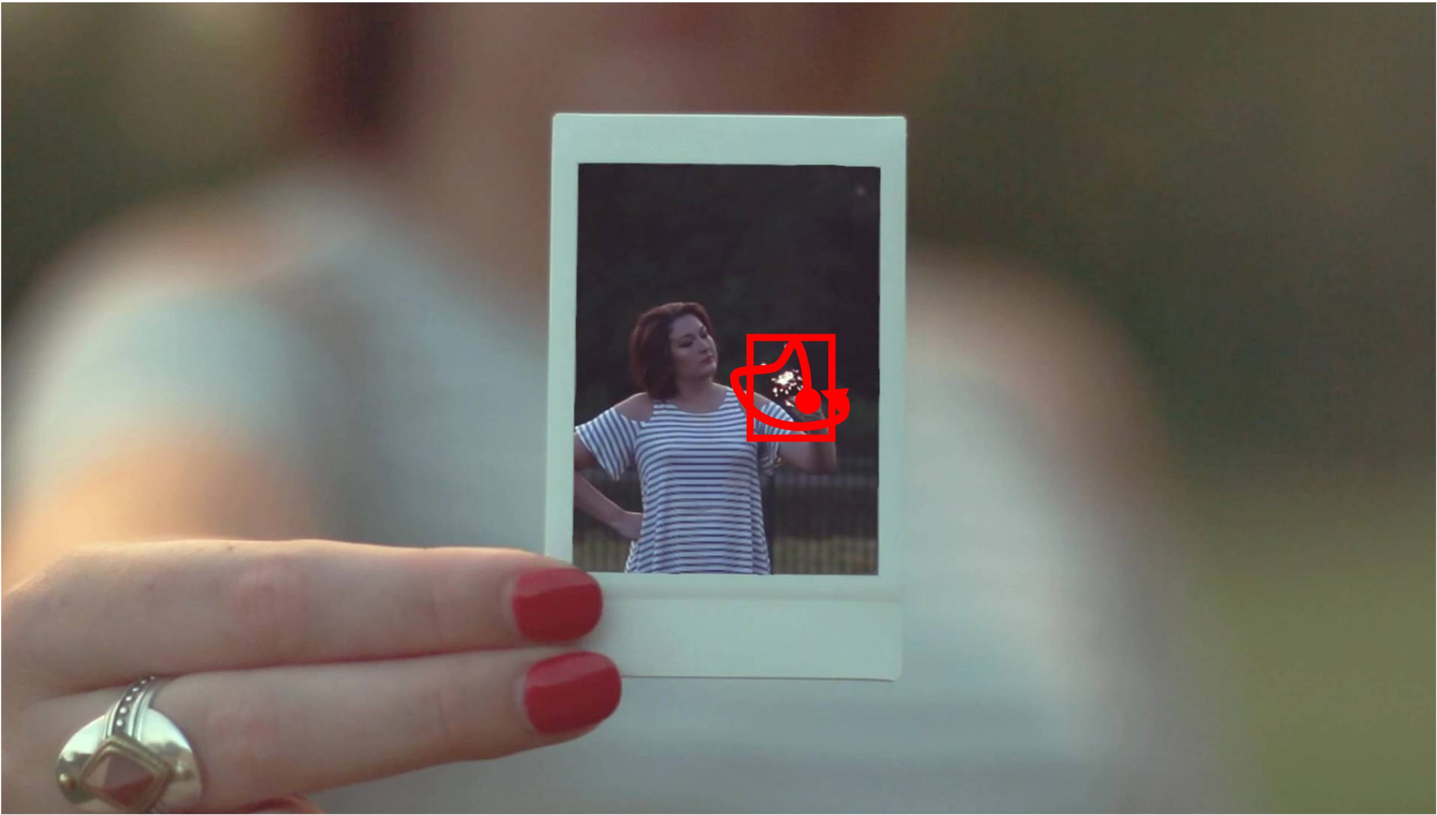 A close-up shot of a woman holding a photograph. The photograph contains a woman who is holding a firework. The woman in the photograph is playing with the firework, moving it around while staying in the same posture. Everything else in the scene remains static. The shot is taken with a static camera. Camera remains stationary. Static Camera. Camera locked down at the same place. The video loops back to the beginning of the video after it reaches the end.